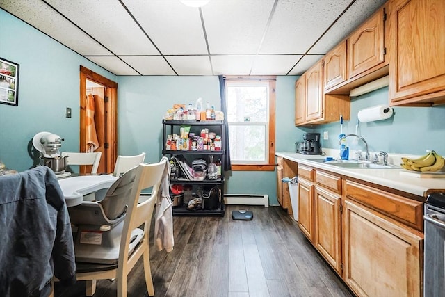 kitchen with dark wood-type flooring, a paneled ceiling, sink, and a baseboard heating unit