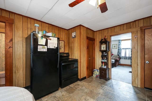 kitchen featuring black appliances, ceiling fan, and wood walls