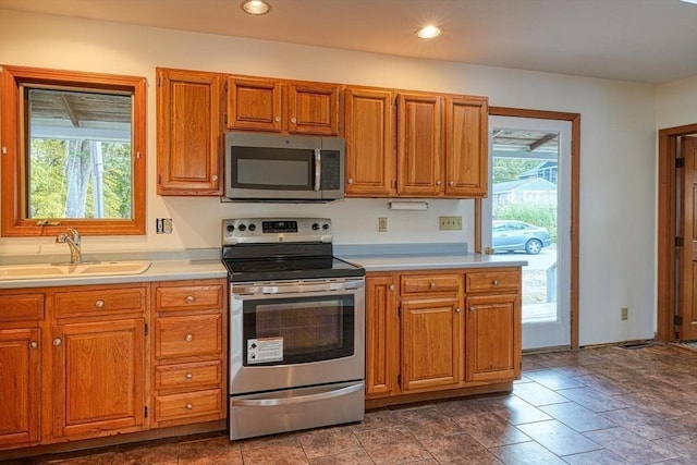 kitchen featuring stainless steel appliances, plenty of natural light, a sink, and light countertops