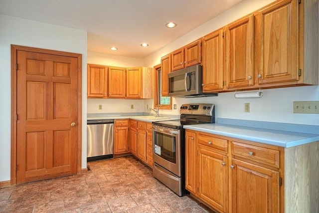 kitchen featuring appliances with stainless steel finishes, brown cabinets, stone finish flooring, light countertops, and recessed lighting