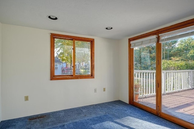 carpeted spare room featuring a healthy amount of sunlight and visible vents