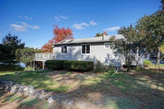 view of side of property with a chimney, a yard, and a deck