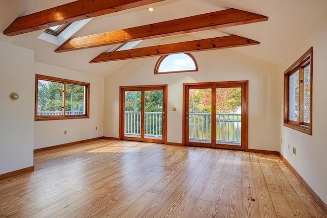 empty room featuring a skylight, baseboards, light wood-style flooring, high vaulted ceiling, and beam ceiling