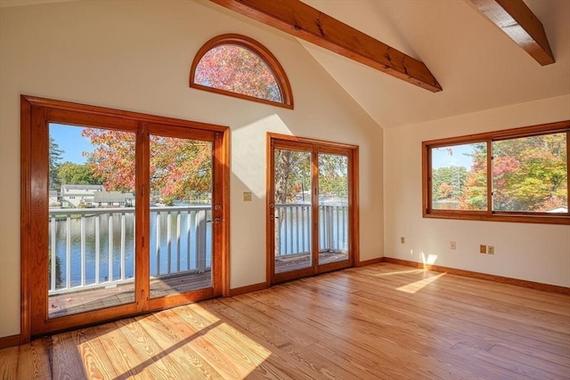 doorway with a water view, light wood-style flooring, baseboards, and beamed ceiling