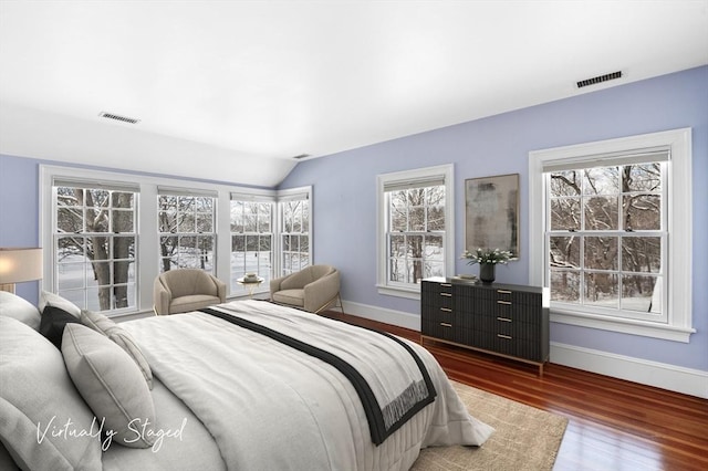 bedroom featuring lofted ceiling, baseboards, visible vents, and wood finished floors