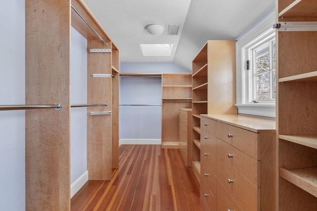 walk in closet with lofted ceiling with skylight, light wood-type flooring, and visible vents