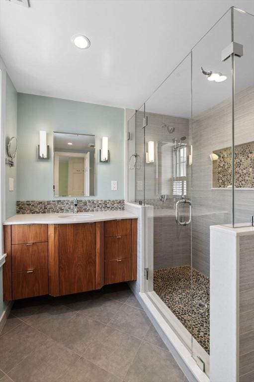 bathroom with backsplash, a shower stall, vanity, and tile patterned floors