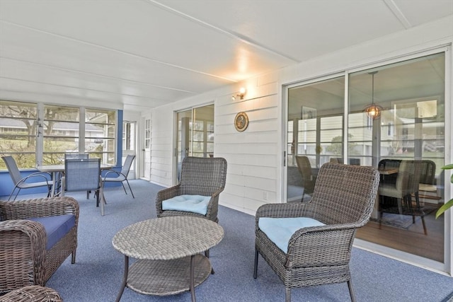sunroom / solarium with outdoor dining area, carpet floors, and an outdoor living space
