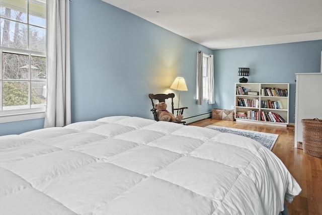 bedroom featuring wood finished floors and a baseboard radiator