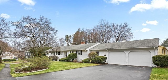 single story home featuring a garage, driveway, a chimney, and a front yard