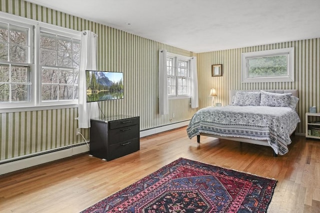 bedroom featuring a baseboard radiator, wood finished floors, and wallpapered walls