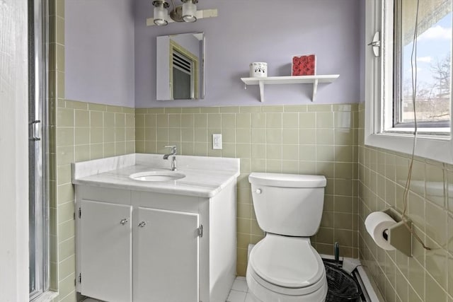 bathroom with tile walls, toilet, vanity, and a wainscoted wall