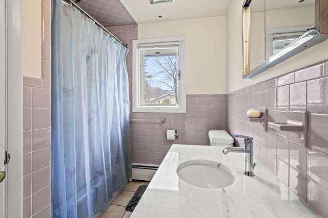 full bathroom with tile patterned floors, tile walls, baseboard heating, curtained shower, and vanity