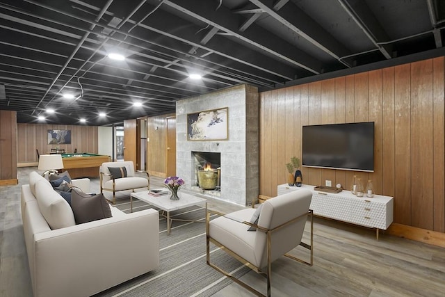 living area featuring wood finished floors, pool table, wooden walls, and a tile fireplace
