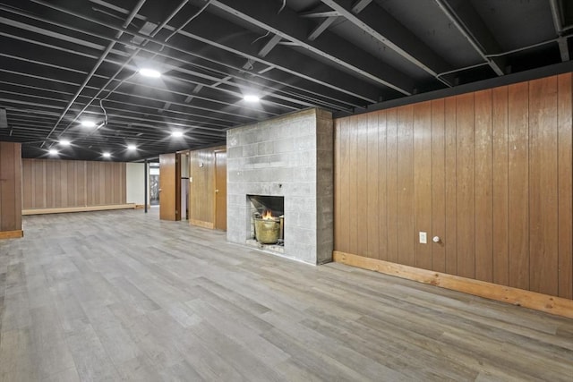 finished basement with baseboards, wooden walls, wood finished floors, and a fireplace