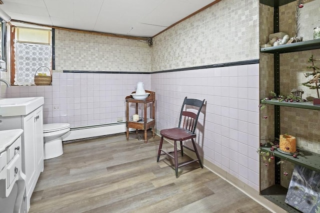 bathroom featuring a baseboard radiator, wood finished floors, and tile walls