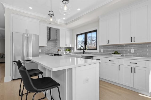 40 Maplewood Unit 40, Boston, MA 02132 - kitchen with stainless steel appliances, a kitchen island, light wood-style floors, wall chimney range hood, and white cabinets