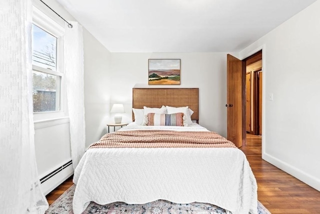 bedroom with baseboards, baseboard heating, and wood finished floors