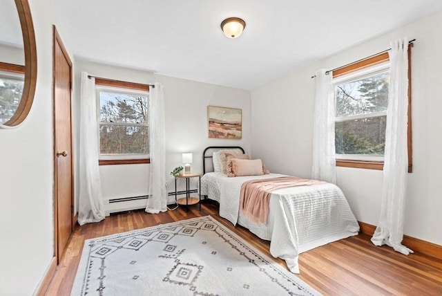 bedroom featuring baseboards, a baseboard heating unit, and wood finished floors