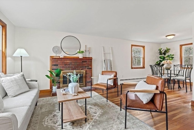 living room with a baseboard radiator, a brick fireplace, and wood finished floors