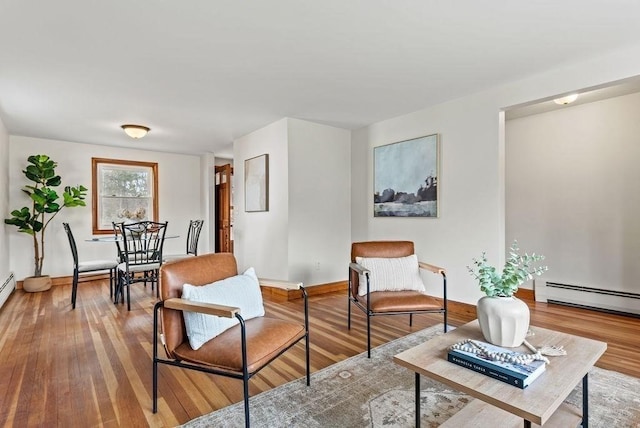 sitting room with baseboards, baseboard heating, and wood finished floors