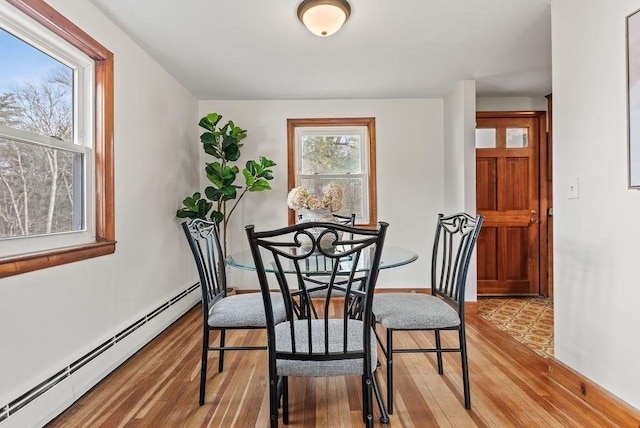 dining room with a baseboard heating unit and wood finished floors