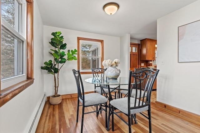 dining room featuring a baseboard radiator, light wood-style flooring, and baseboards