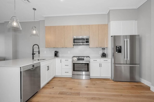 kitchen featuring a sink, white cabinetry, light countertops, appliances with stainless steel finishes, and decorative light fixtures