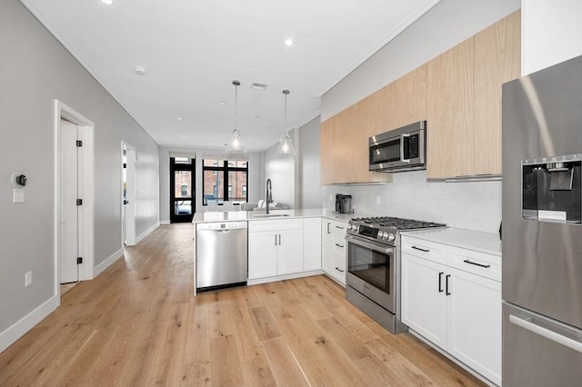 kitchen featuring pendant lighting, stainless steel appliances, light countertops, a sink, and a peninsula