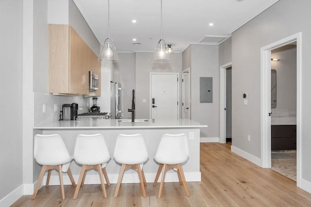 kitchen featuring a breakfast bar, light countertops, hanging light fixtures, and light brown cabinets