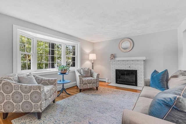 16 Vanderbelt Rd, Acton, MA 01720 - living area with a baseboard heating unit, wood finished floors, a brick fireplace, and a textured ceiling