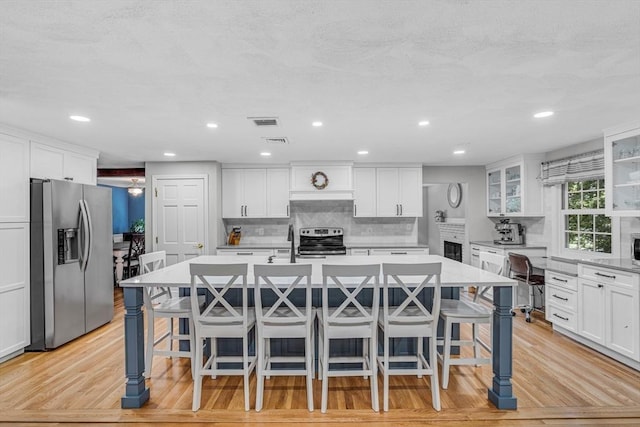 16 Vanderbelt Rd, Acton, MA 01720 - kitchen with appliances with stainless steel finishes, a breakfast bar area, light countertops, a center island with sink, and recessed lighting