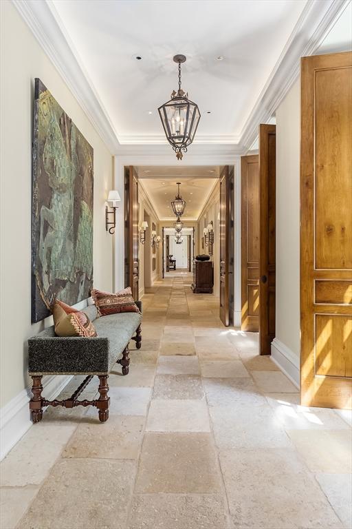180 Ash St, Weston, MA 02493 - corridor featuring stone tile flooring, a chandelier, a tray ceiling, ornamental molding, and baseboards