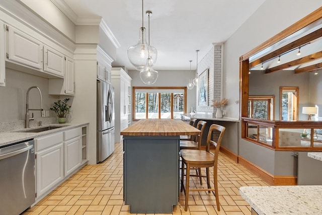 kitchen with appliances with stainless steel finishes, white cabinets, butcher block countertops, and a sink