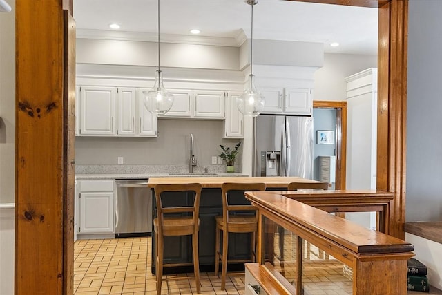 kitchen with stainless steel appliances, white cabinets, a sink, and crown molding