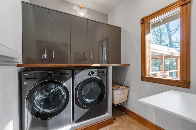 laundry area featuring light tile patterned flooring, independent washer and dryer, cabinet space, and baseboards