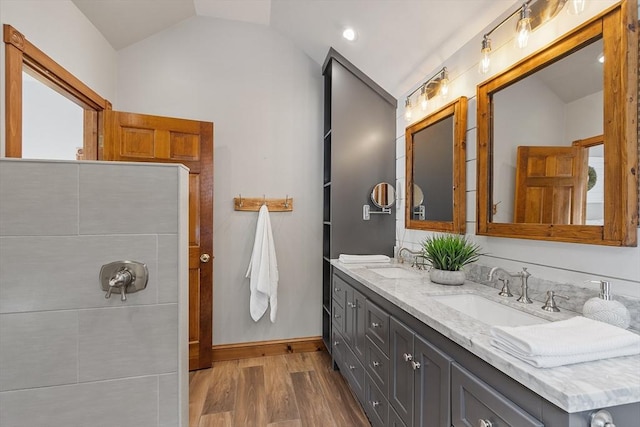 full bath featuring double vanity, vaulted ceiling, a sink, and wood finished floors