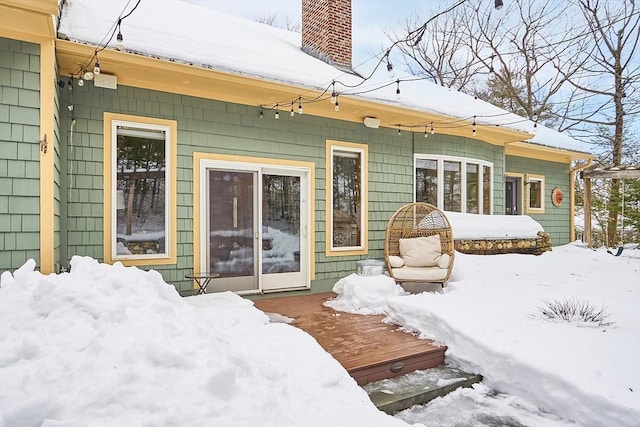 snow covered back of property featuring a chimney