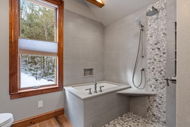 bathroom with lofted ceiling, toilet, wood finished floors, baseboards, and tiled shower