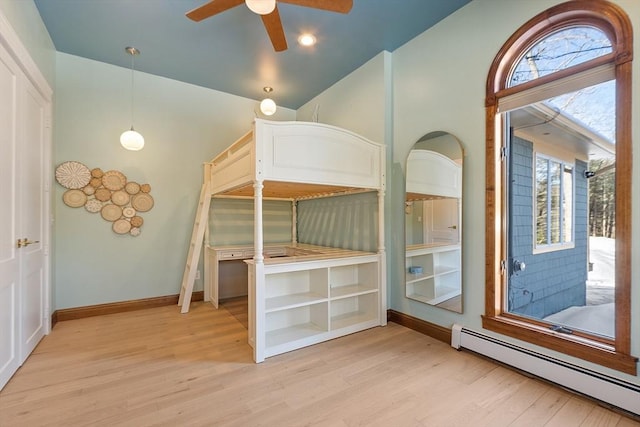 unfurnished bedroom with light wood-type flooring, a baseboard radiator, multiple windows, and baseboards