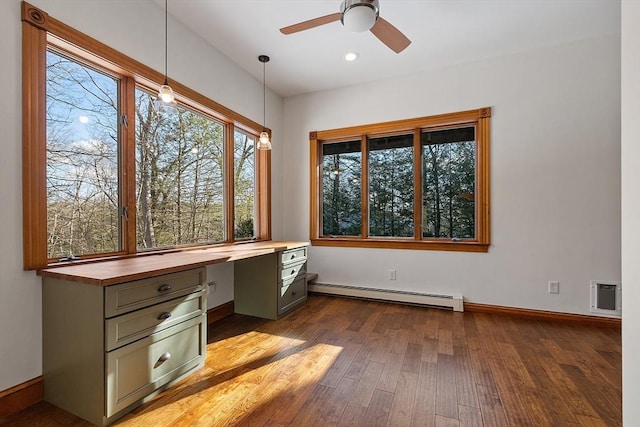 unfurnished office with baseboards, built in study area, ceiling fan, dark wood-style flooring, and a baseboard heating unit