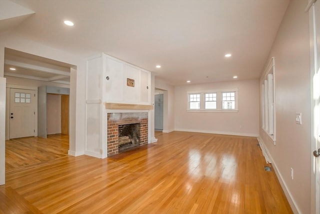 unfurnished living room with light hardwood / wood-style flooring and a brick fireplace