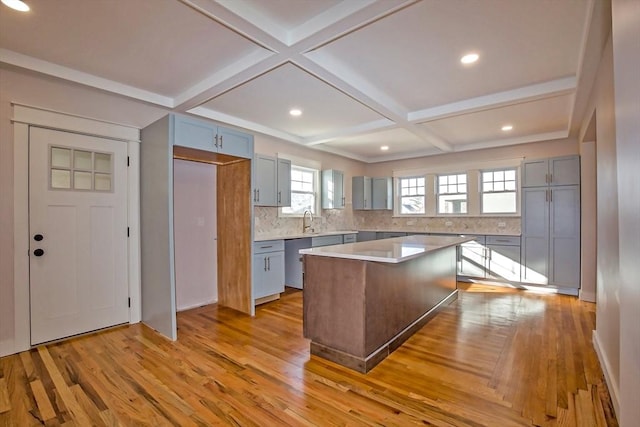 kitchen featuring sink, light hardwood / wood-style flooring, stainless steel dishwasher, backsplash, and a kitchen island