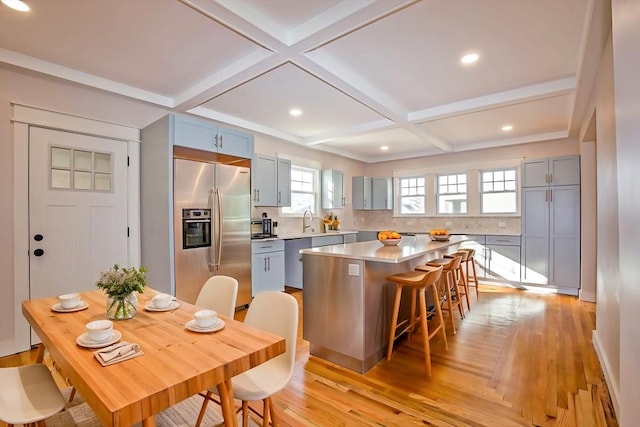 kitchen with sink, coffered ceiling, a breakfast bar area, a kitchen island, and appliances with stainless steel finishes