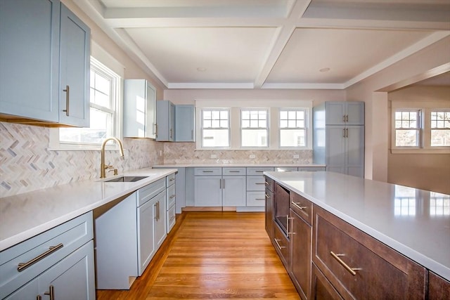 kitchen with backsplash, sink, light hardwood / wood-style floors, and beam ceiling