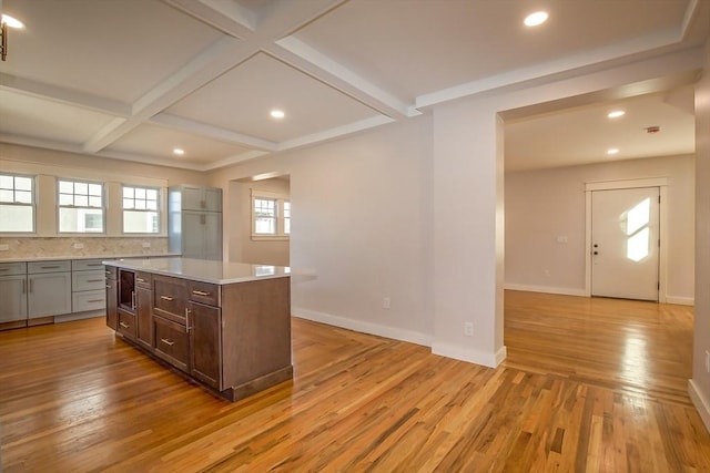 kitchen with backsplash, coffered ceiling, light wood-type flooring, beam ceiling, and a kitchen island