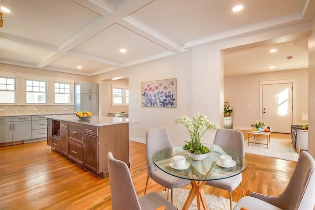 dining area featuring beamed ceiling, light hardwood / wood-style floors, and coffered ceiling