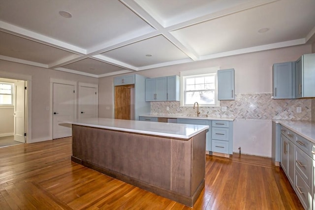 kitchen featuring sink, coffered ceiling, dark hardwood / wood-style flooring, decorative backsplash, and a kitchen island