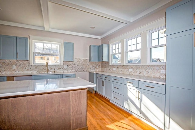 kitchen featuring beamed ceiling, light hardwood / wood-style floors, tasteful backsplash, and sink