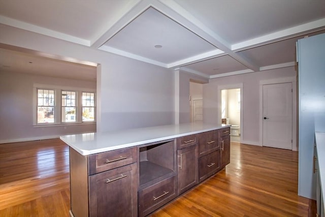 kitchen featuring light wood-type flooring, coffered ceiling, built in desk, beamed ceiling, and a center island